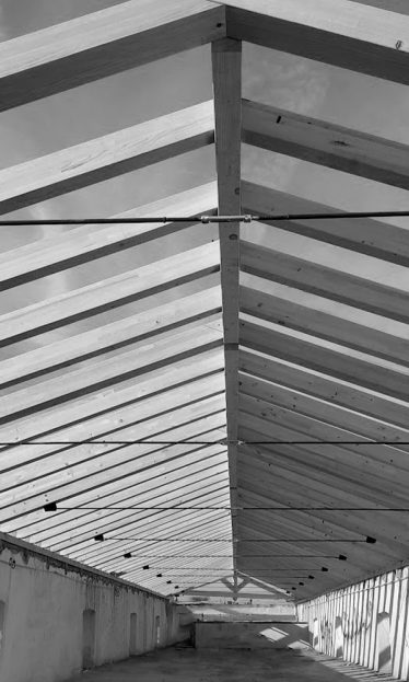 Estructura de madera en la última planta de un módulo de nave industrial, casi al alcance de los dedos. Detalle cercano que muestra la solidez y la belleza de la madera en la construcción industrial. Proyecto en fase final de construcción que resalta la elegancia y la funcionalidad de la madera como material estructural.